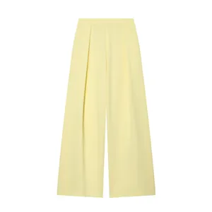 Vista dettagliata dei pantaloni larghi giallo pallido con design a pieghe.