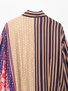 Primo piano di vivaci motivi misti su una camicia di raso con strisce e stampe floreali.