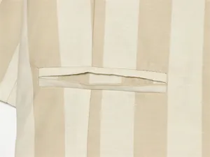 Gros plan sur les coutures de la poche d'un blazer d'été court à rayures beiges et blanches