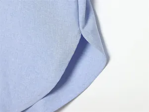 Gros plan sur l'ourlet incurvé et les coutures de qualité de cette chemise en lin bleu clair