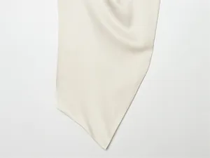Primer plano de la textura de tela de seda blanco roto con caída suave y brillo.