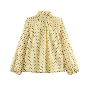 Close-up of elegant cream long-sleeved blouse with brown polka dot print pattern