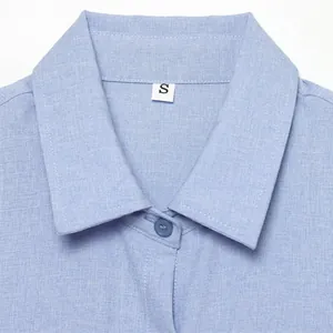 Détail du col d'une chemise en lin bleu clair avec étiquette taille S et bouton assorti