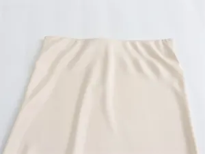 Primer plano de la falda larga de satén de seda beige con cintura alta y textura suave
