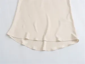 Detalle del dobladillo curvo de una falda larga de satén de seda beige estilo francés.