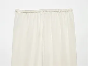 Detalle de pantalón de satén de seda marfil con cintura elástica y tejido suave.