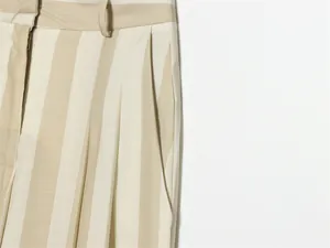Gros plan détaillé du pantalon à rayures beiges et crème avec plis et poche latérale