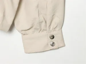 Gros plan détaillé du poignet de manche lanterne beige avec boutons-pression argentés