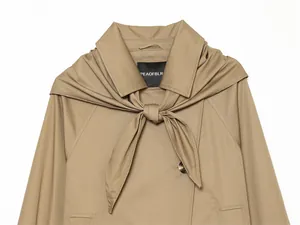 Primer plano de una gabardina corta color caqui con un elegante lazo de bufanda a juego.