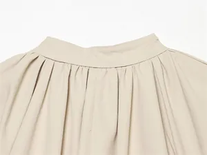 Vue détaillée de l'encolure plissée et des coutures d'une veste à manches lanternes beige.