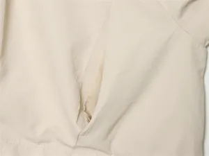 Vue macro montrant les coutures fines et la texture du tissu beige de la veste d'été