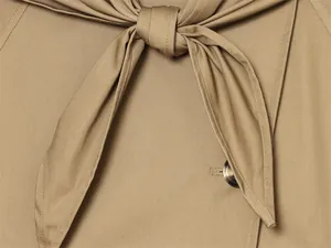 Detalle de primer plano del nudo de la bufanda a juego en una gabardina caqui de moda