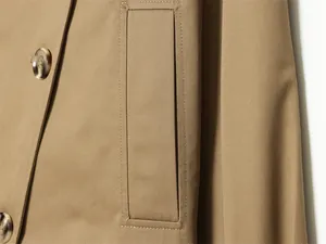 Detalle de cerca del bolsillo y los botones en una clásica gabardina de otoño camel