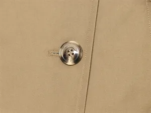 Primer plano del botón jaspeado en una chaqueta gabardina de sarga color caqui.