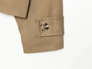Detalle del puño de una gabardina corta de color caqui con botón efecto mármol.