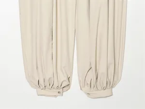 Gros plan détaillé d'un pantalon lanterne d'été beige avec revers plissés et boutonnés