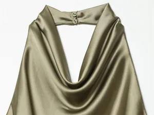 Detalle de top de satén verde oliva con cuello halter y un elegante escote drapeado.