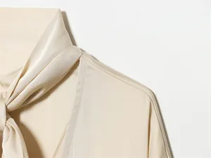 Gros plan d'une robe élégante en satin champagne avec col lavallière et coutures