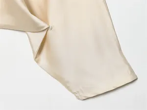 Gros plan de la manche d'une robe en satin champagne avec bouton perle élégant.