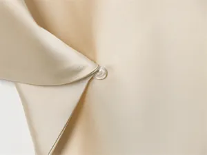 Gros plan sur un luxueux tissu en satin doré champagne avec un bouton perlé délicat