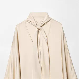 Robe élégante en satin champagne avec col lavallière pour un look d'hiver sophistiqué.