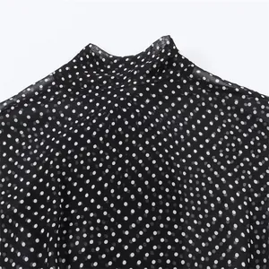 Nahaufnahme des Stehkragens und des weißen Punktmusters auf schwarzer Chiffonbluse