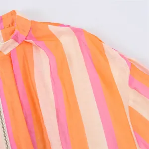 Detail of a pink and orange striped jacket with silver zipper and stand collar.