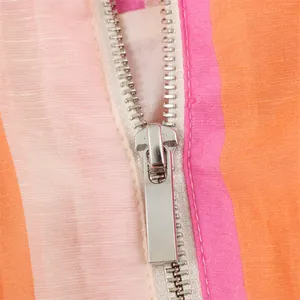 Macro detail of high-quality silver metal zipper on a colorful striped casual jacket