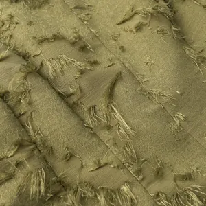 Detailed macro view of olive green fringed jacquard fabric showing intricate tassel texture