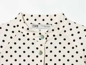 Detailopname van een polka dot blousekraag met iriserende schelpknopen