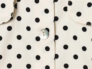 Macro-overzicht van de polka dot hemdjas met getextureerde stof en parelmoer knoop.