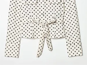 Detail van een wit overhemdjack met stippen, voorzien van een tailleband en knopen