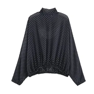 Detailaufnahme einer schwarz-weißen Punktebluse mit Stehkragen und Gummizug am Saum