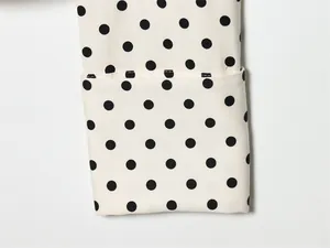 Detailopname van de manchet van een wit katoenen overhemd met zwart polkadot patroon.