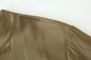 Close-up of shoulder stitching and knot button on a satin olive green casual shirt