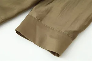 Close-up of olive green silky fabric and wide cuff detail on a loose casual shirt