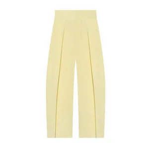 Close-up detail of high-waisted pleated balloon trousers in stylish pale yellow fabric.
