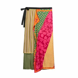 Detail showing the colorful patchwork patterns and black waist tie of the wrap skirt.