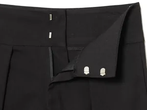 Close-up of waistband with double hook-and-eye closure and zipper fly on black trousers.