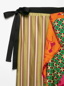 Close-up detail of vibrant floral and striped patterns on a silk-like wrap skirt