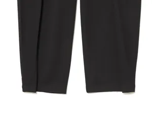 Close-up detail of the hem and pleated fabric texture on black balloon-style trousers