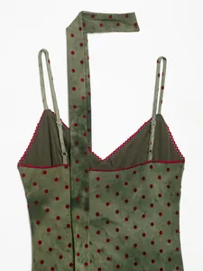Detail of vintage green tie-dye slip dress with red polka dots and halter strap neck