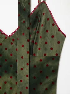 Detailed view of moss green mesh dress with red velvet polka dots and scalloped trim
