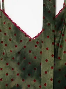 Close-up macro detail of green dress featuring red velvet polka dots and lace trim