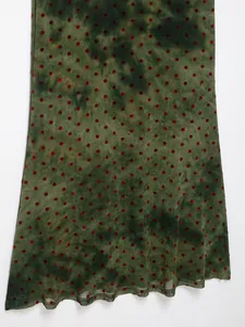 Detail of green tie-dye mesh fabric with red velvet polka dots on a slim fit dress.