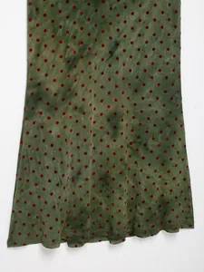Macro view of green tie-dye mesh fabric featuring red velvet polka dots on a dress