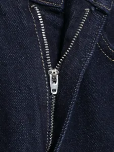 Detailaufnahme des robusten Metallreißverschlusses an einer dunkelblauen Jeans für Damen