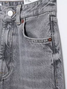 Makroaufnahme der Textur und Taille einer grauen High-Rise-Jeans mit Kupfernieten