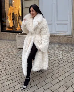 Elegant woman wearing long white faux fur coat on a European street scene.
