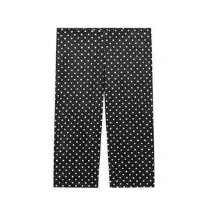 Gedetailleerde weergave van zwarte Capri-broek met witte stippen en rechte pijpen.